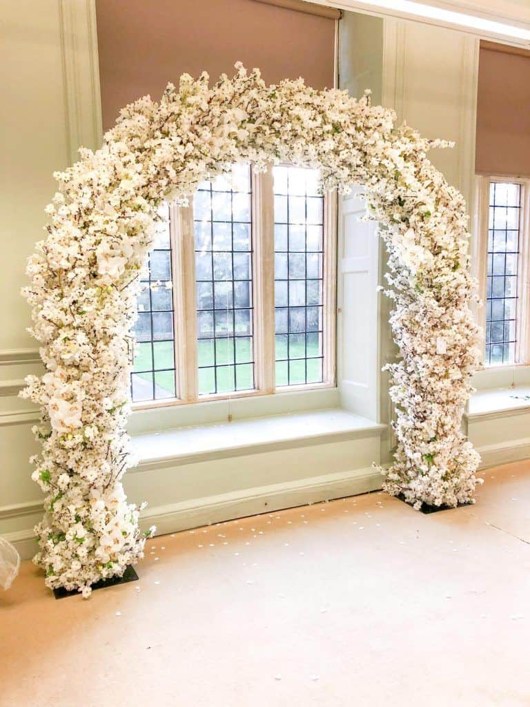 A room with a decoratively adorned archway of white flowers available for hire.
