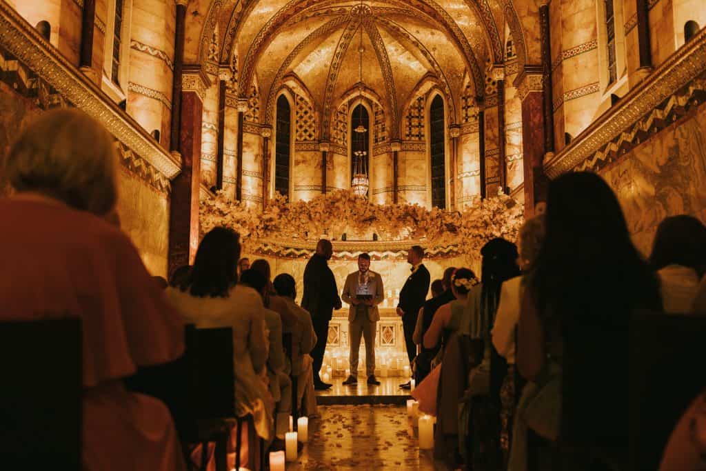 A wedding ceremony in an ornate building with candles.