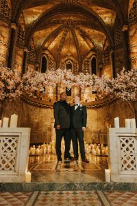 Two men standing in front of candles in a church.