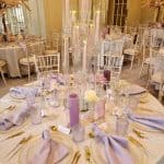 A table setting with purple and white tablecloths and candles.