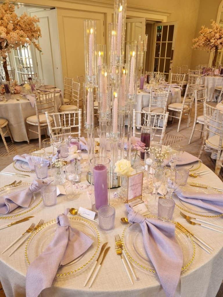 A table setting with purple and white tablecloths and candles.