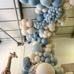 A room filled with blue and white balloons and a giraffe.