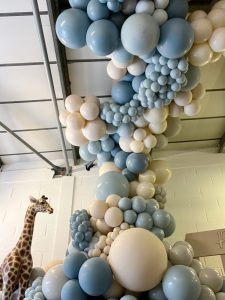 A room filled with blue and white balloons and a giraffe.