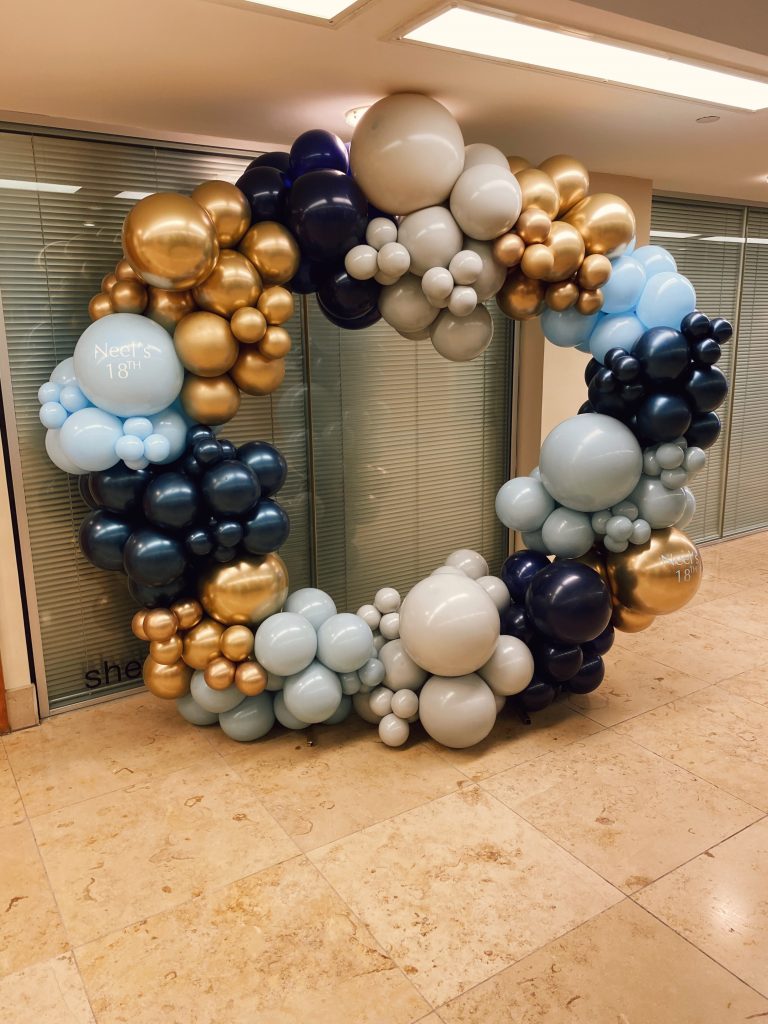 A balloon hoop made of blue and gold balloons.