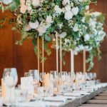 A long table set with white flowers and greenery.