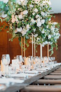 A long table set with white flowers and greenery.