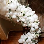 A white balloon arch on a wooden staircase.