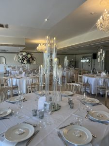 A wedding reception with white tablecloths and candles.