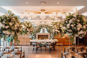 A wedding ceremony set up in a room with white flowers and a chandelier.